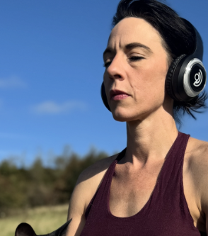 Breather with headphones, eyes closed under open sky